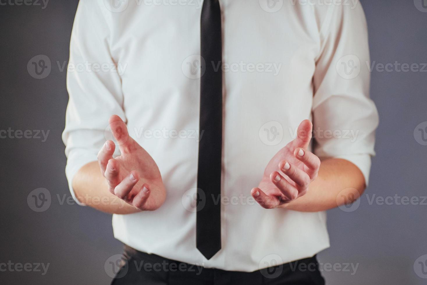 le jeune homme d'affaires en costume montre sa main sur un fond sombre isolé photo