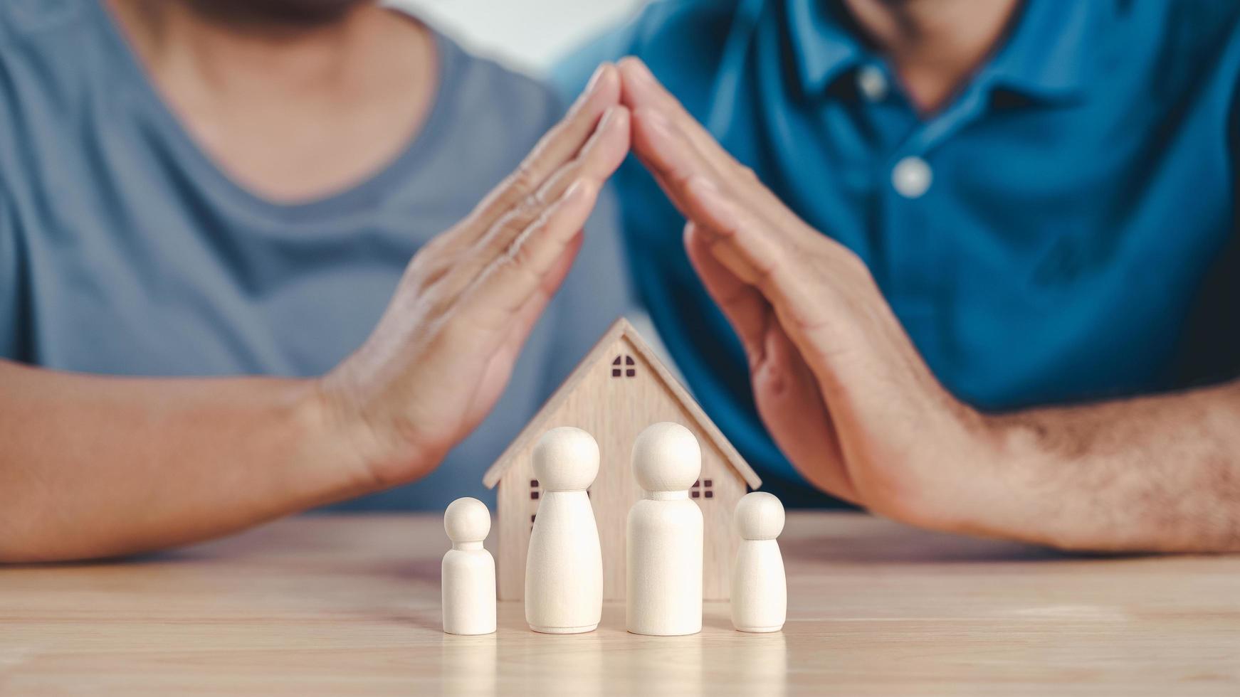 les mains de l'homme et de la femme protègent les poupées en bois. planification, épargne familiale, soins de santé et assurance, santé mentale familiale, journée internationale des familles photo