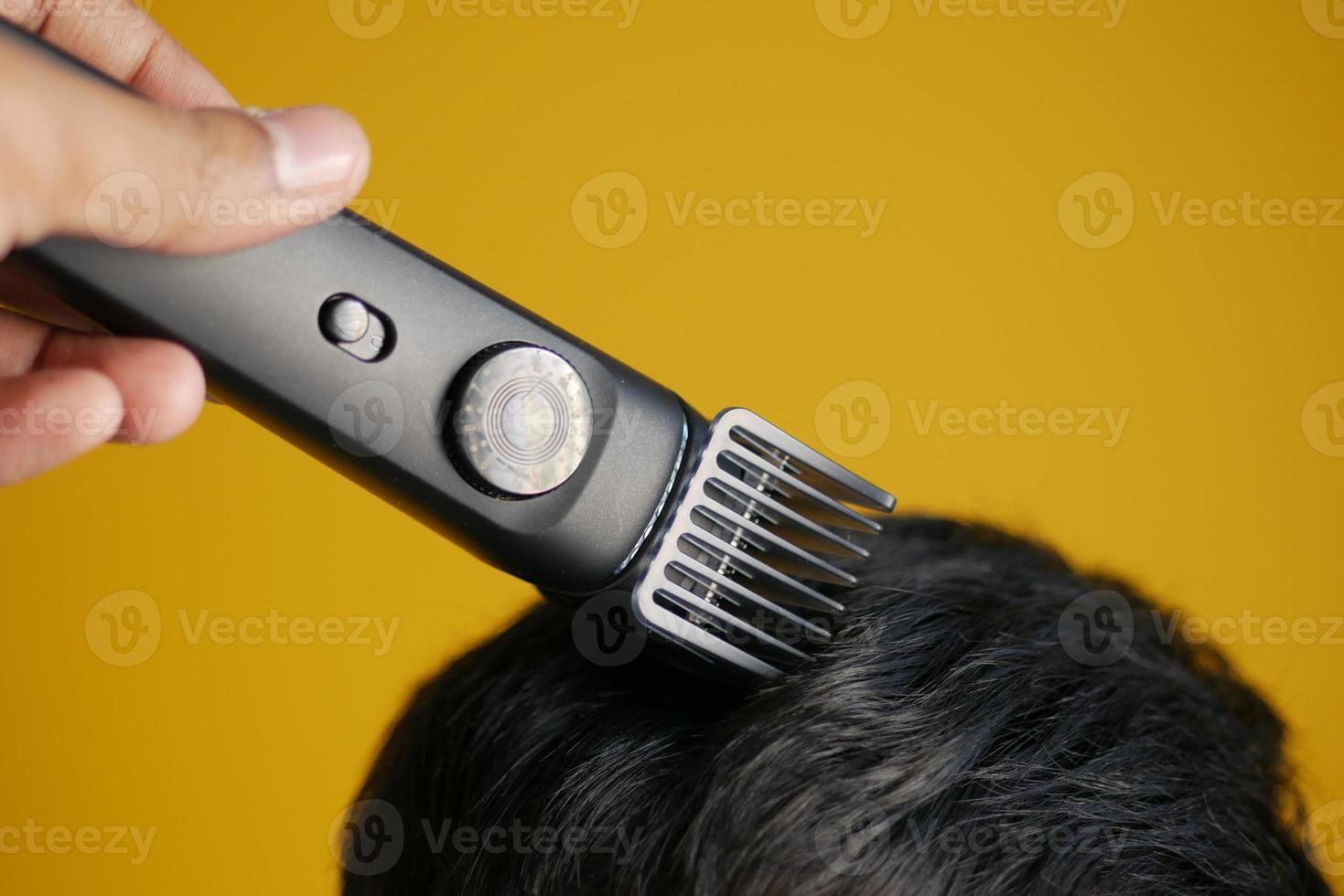 couper les cheveux avec une tondeuse à cheveux sur fond jaune photo