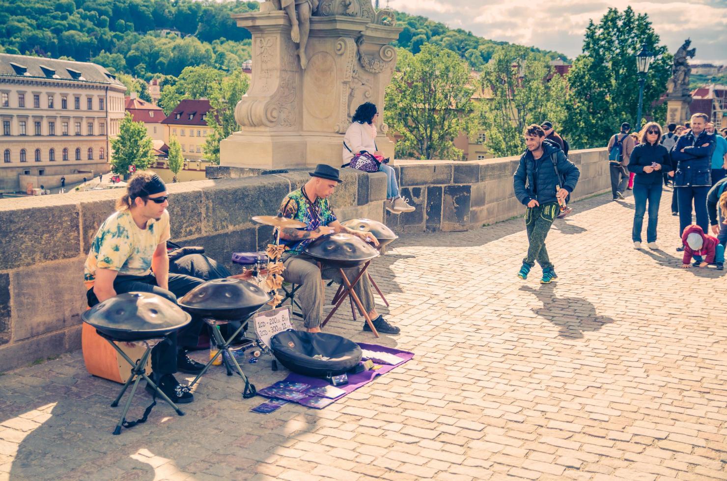 prague, république tchèque, 13 mai 2019 des musiciens de rue jouent leurs instruments de tambour suspendus et l'homme danse sur le pont charles piétonnier pavé karluv most sur la rivière vltava photo