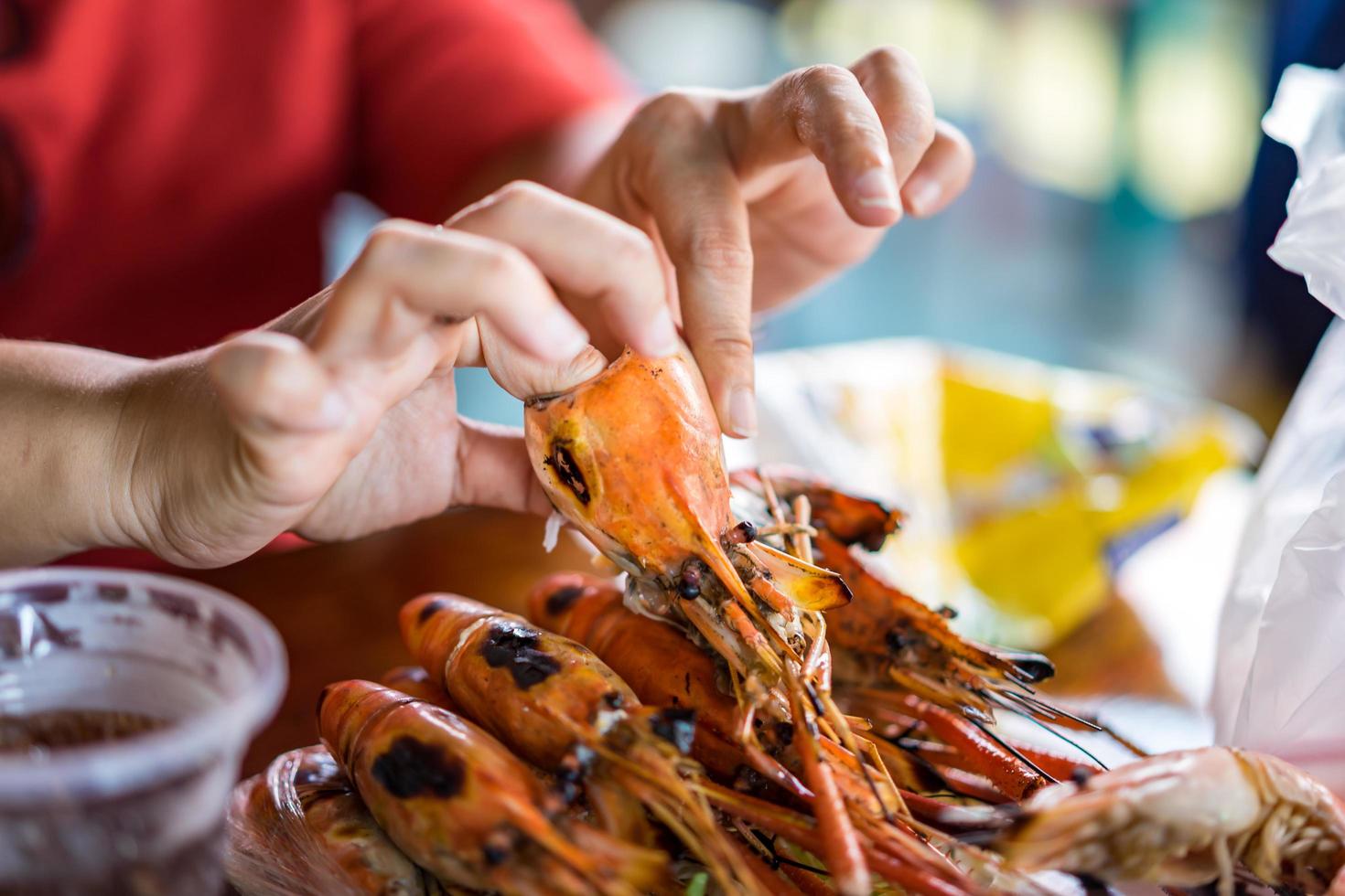 la main de la femme dénude les crevettes grillées. photo