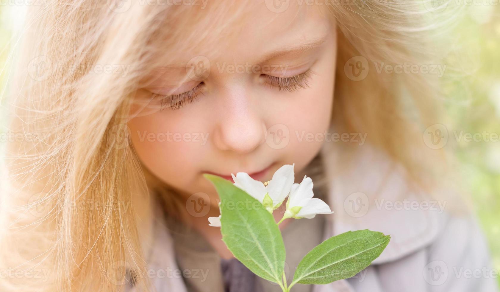 petite fille blonde renifle des fleurs de jasmin photo