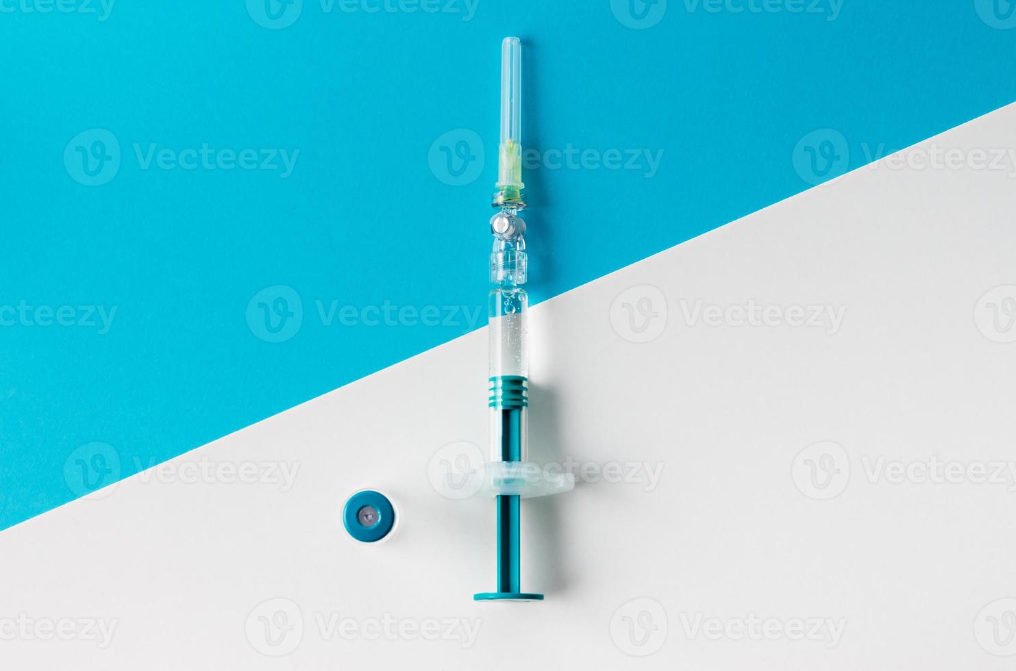 seringue avec flacon médical pour injection sur fond bleu et blanc. vue de dessus. photo
