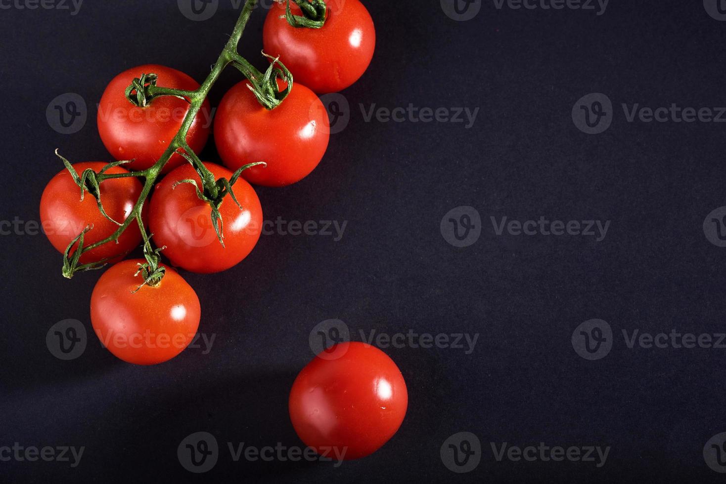 branche de tomates biologiques rouges sur fond noir. photo