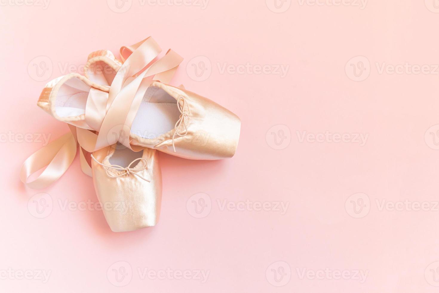 nouvelles chaussures de ballet beige pastel avec ruban de satin isolé sur fond rose. ballerines pointes classiques pour l'entraînement de danse. concept d'école de ballet. vue de dessus à plat, espace de copie photo