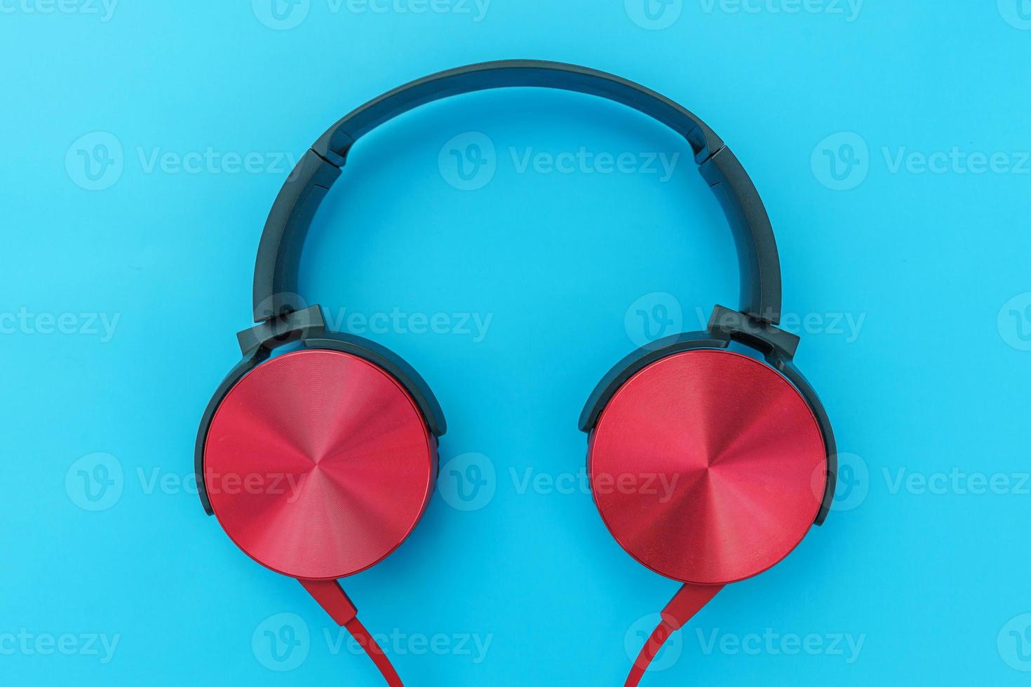 casque rouge sur fond bleu turquoise. photo simple minimaliste d'écouteurs avec espace de copie. casque dj rouge avec câble isolé sur fond coloré pastel, vue de dessus à plat. notion de musique.