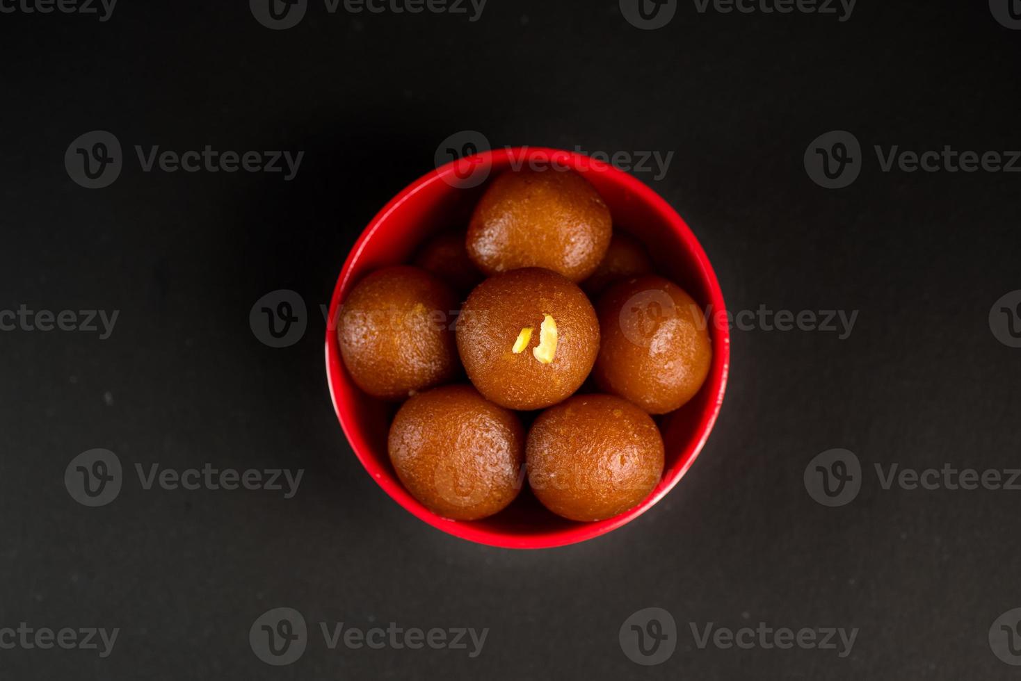 gulab jamun dans un bol sur fond noir. dessert indien ou plat sucré. photo