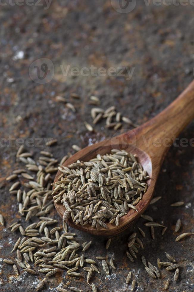 graines de cumin dans une cuillère en bois sur un fond texturé photo