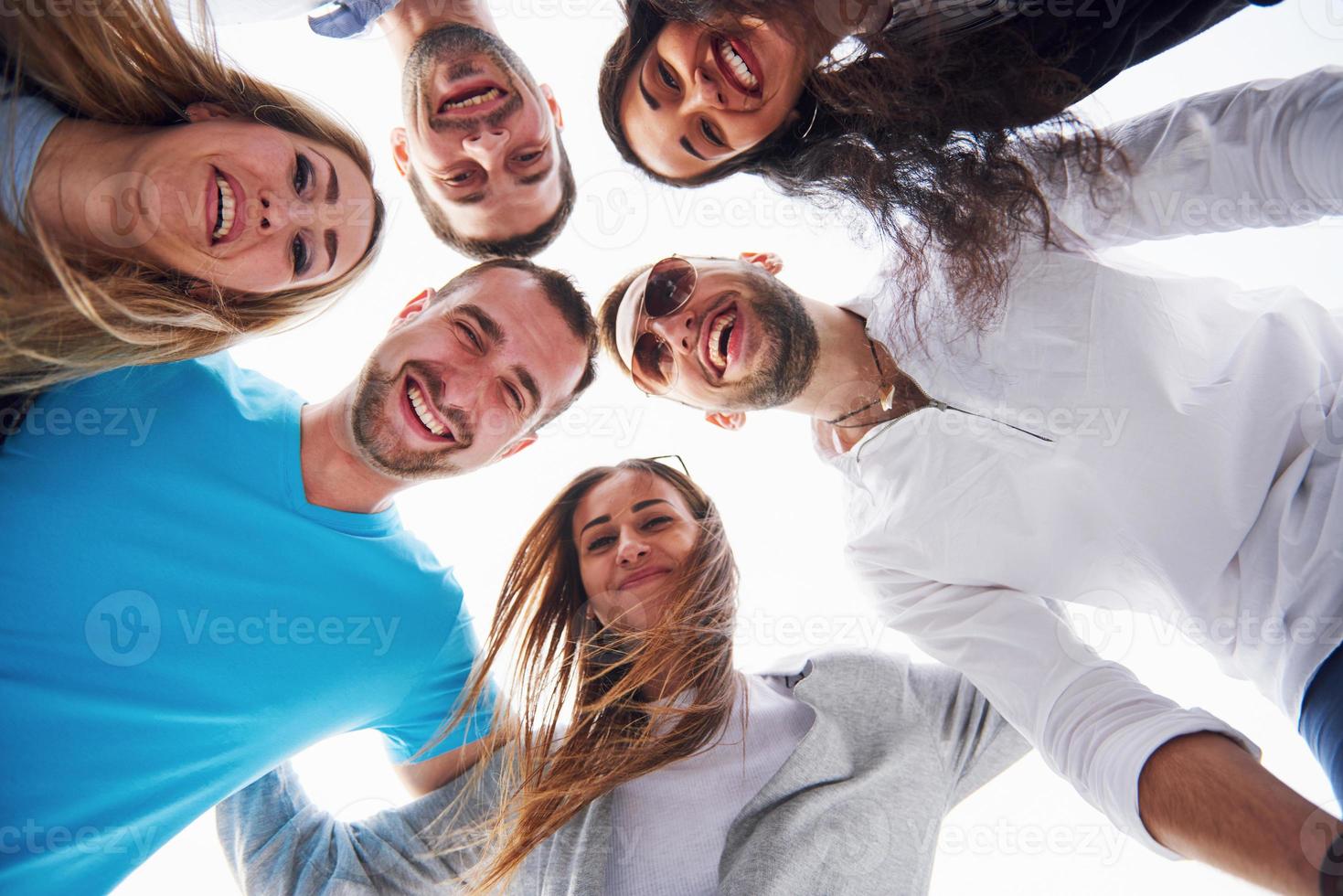 portrait d'un groupe de jeunes assis au bord de la jetée, à l'extérieur dans la nature. amis profitant d'un jeu sur le lac. photo