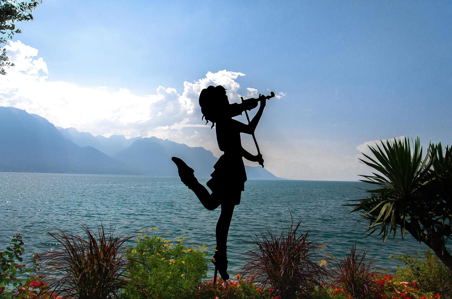 montreux, suisse - 14 septembre 2017 figure silhouette de fille avec violon sur la promenade du lac leman lac leman devant les montagnes alpes, riviera suisse, canton de vaud photo