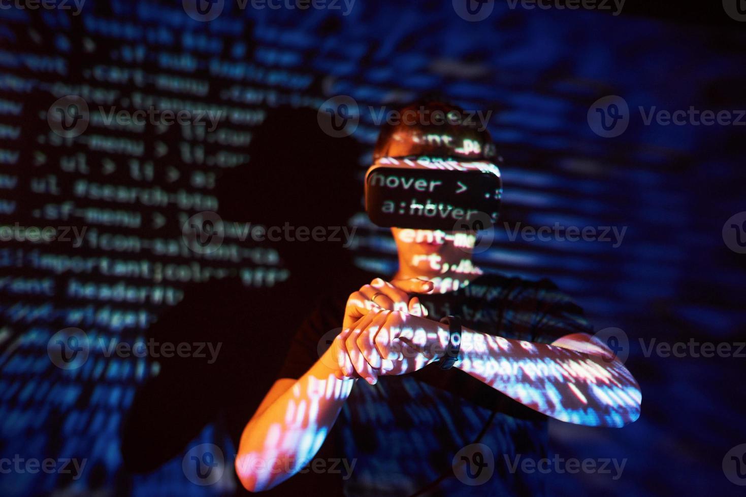 la double exposition d'un homme caucasien et d'un casque de réalité virtuelle est vraisemblablement un joueur ou un pirate qui craque le code dans un réseau ou un serveur sécurisé, avec des lignes de code photo