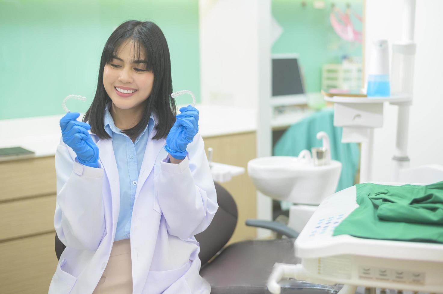 jeune femme dentiste tenant invisalign dans une clinique dentaire, contrôle des dents et concept de dents saines photo