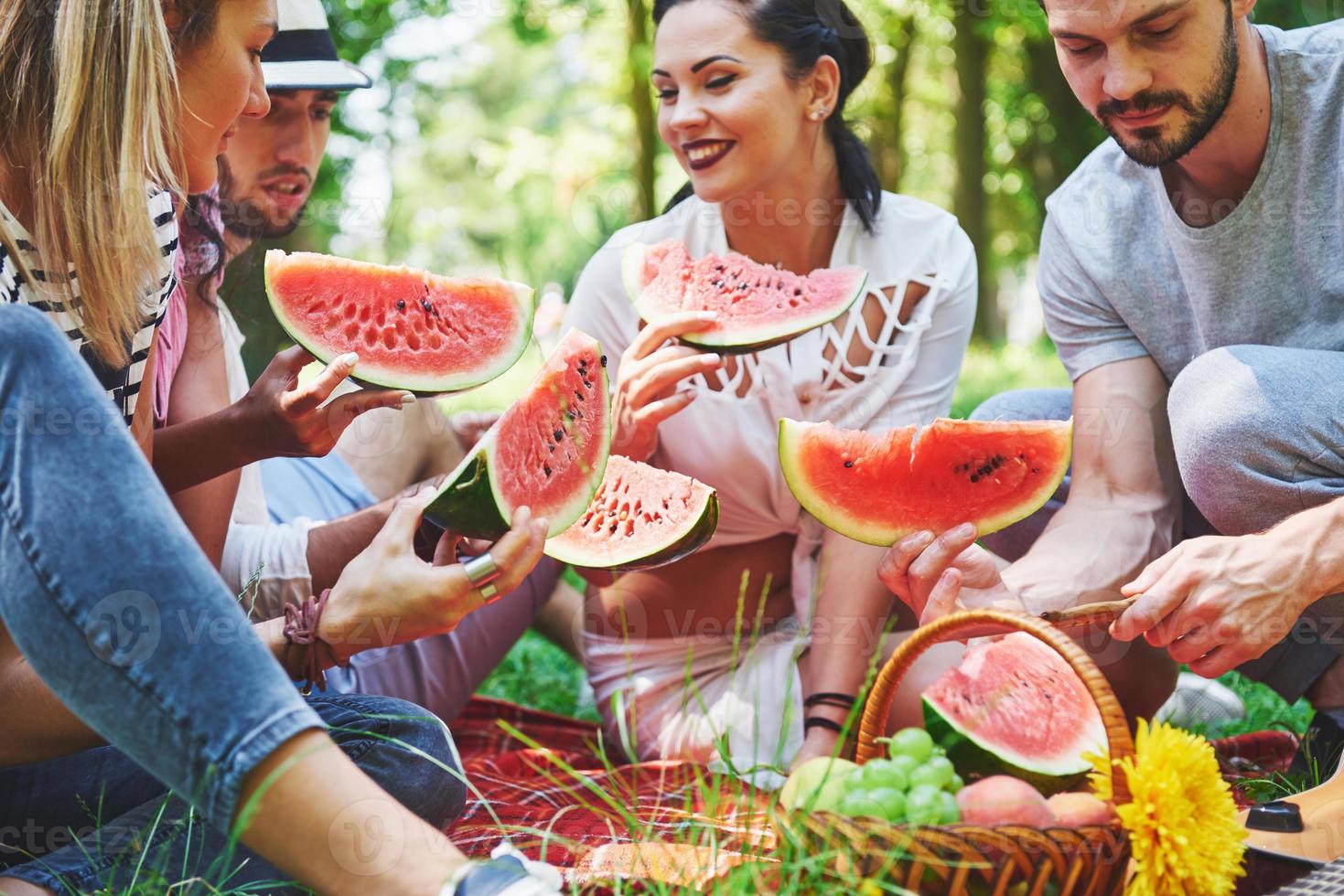 groupe d'amis faisant un pique-nique dans un parc par une journée ensoleillée - les gens traînent, s'amusent en grillant et se détendant photo