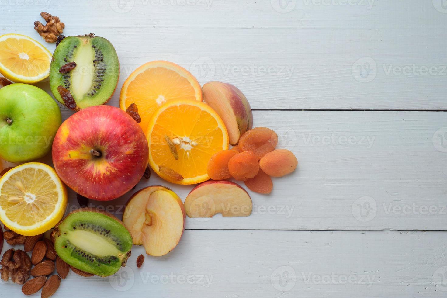 pommes, kiwis, fruits secs, oranges et pommes. concept d'alimentation saine. tourné sur une table en bois blanche. photo