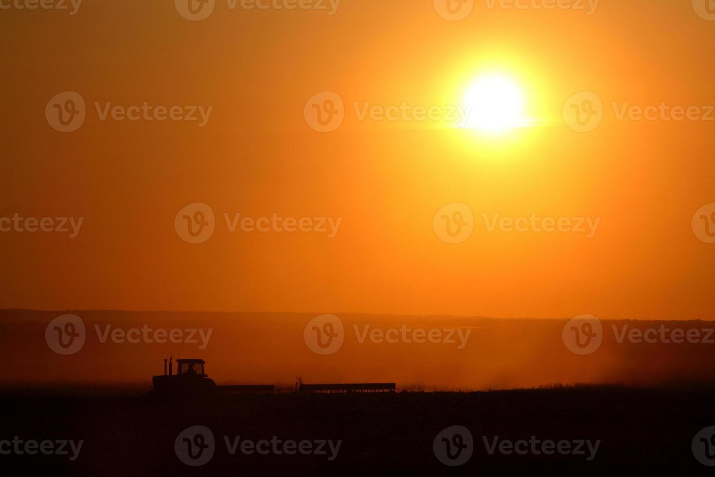 coucher de soleil derrière l'agriculture travaillant ses champs photo