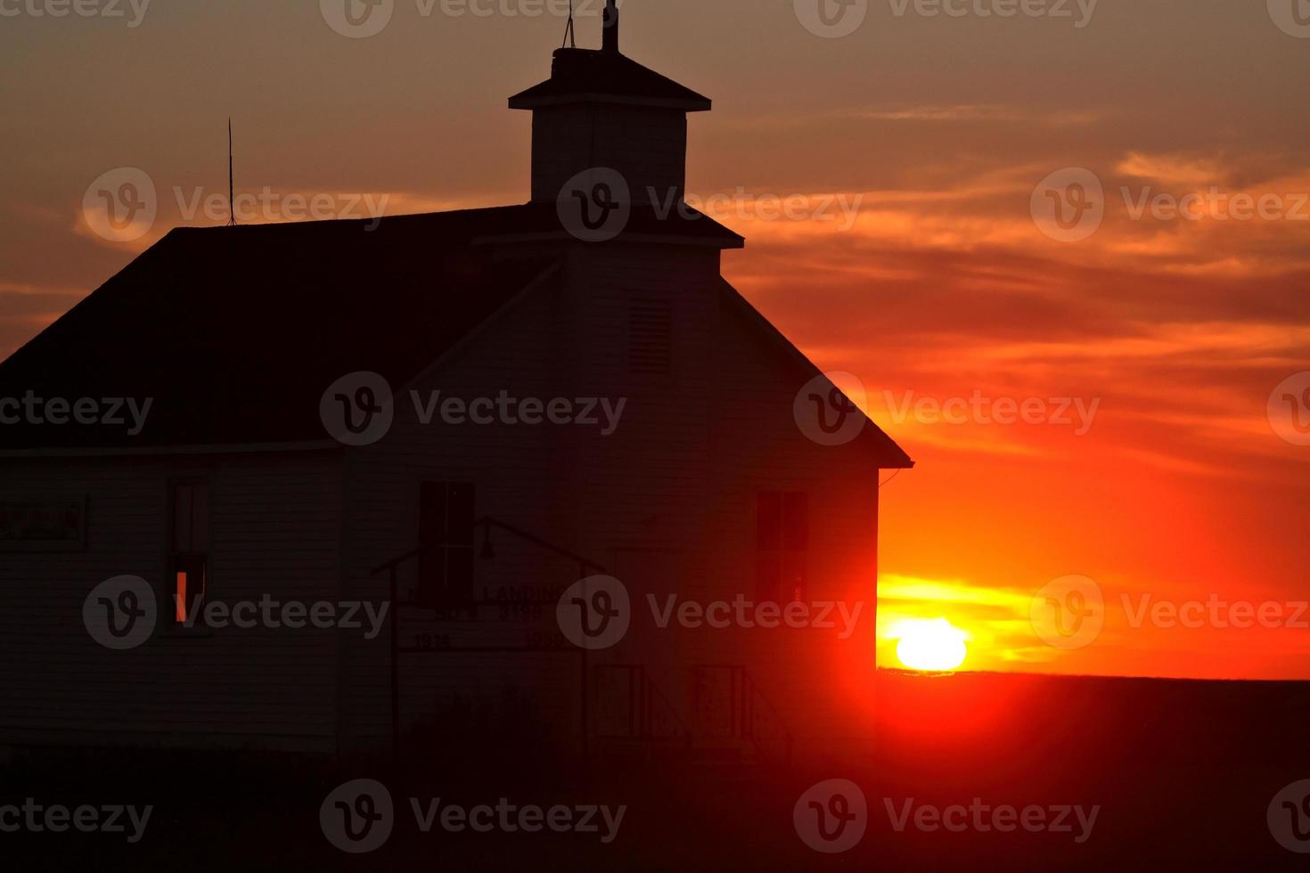 coucher de soleil derrière une ancienne école de campagne dans la pittoresque ville de saskatchewan photo