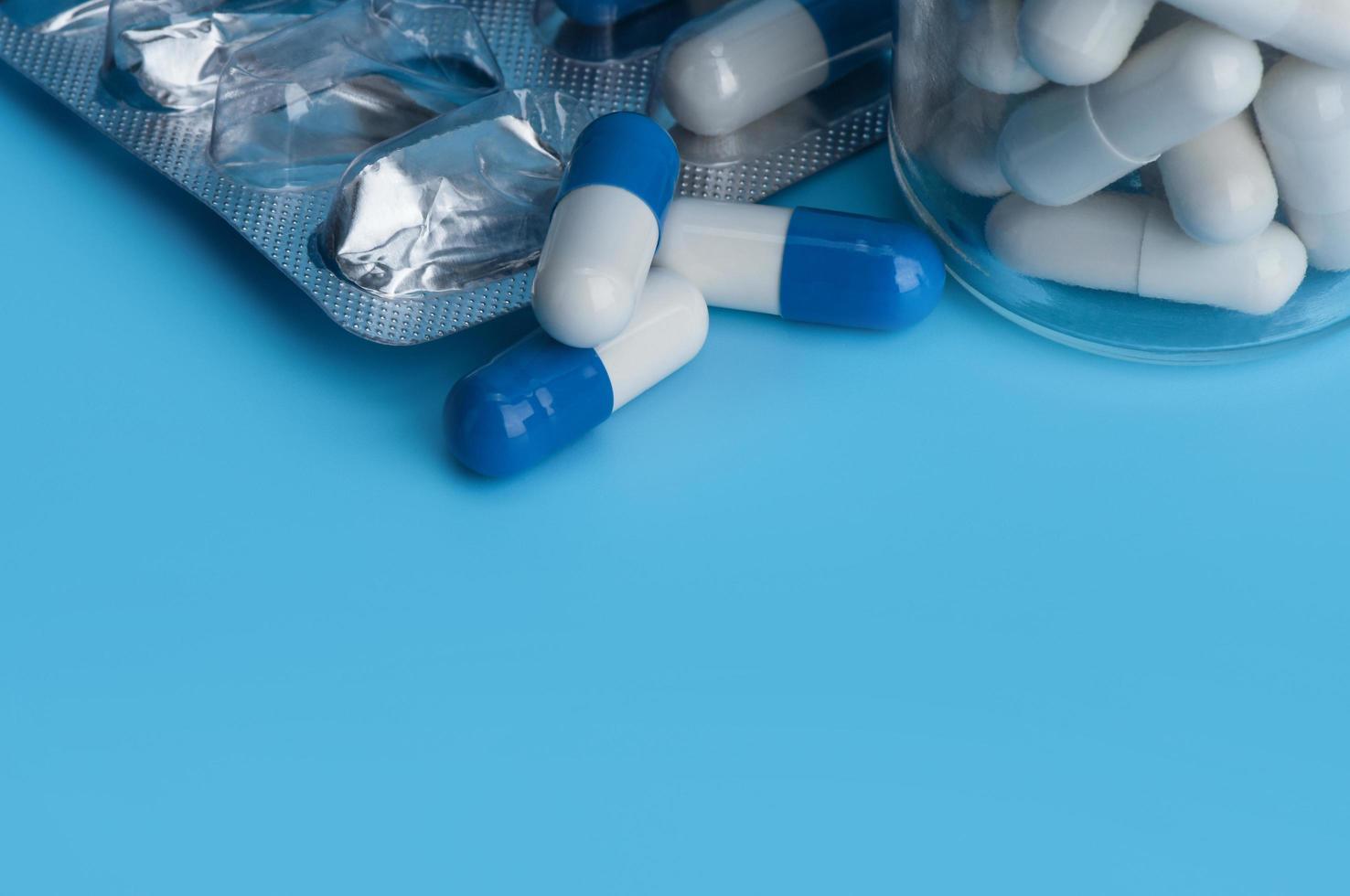 capsules de pilules de médecine sous blister et dans la bouteille sur fond bleu avec espace de copie. photo