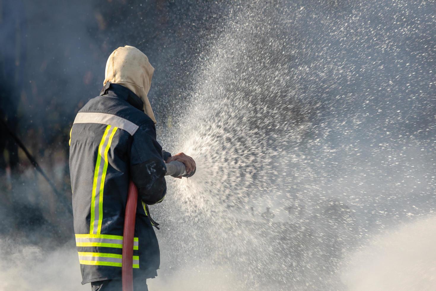 pompier pulvérisant de l'eau à partir d'un gros tuyau d'eau pour prévenir les incendies photo