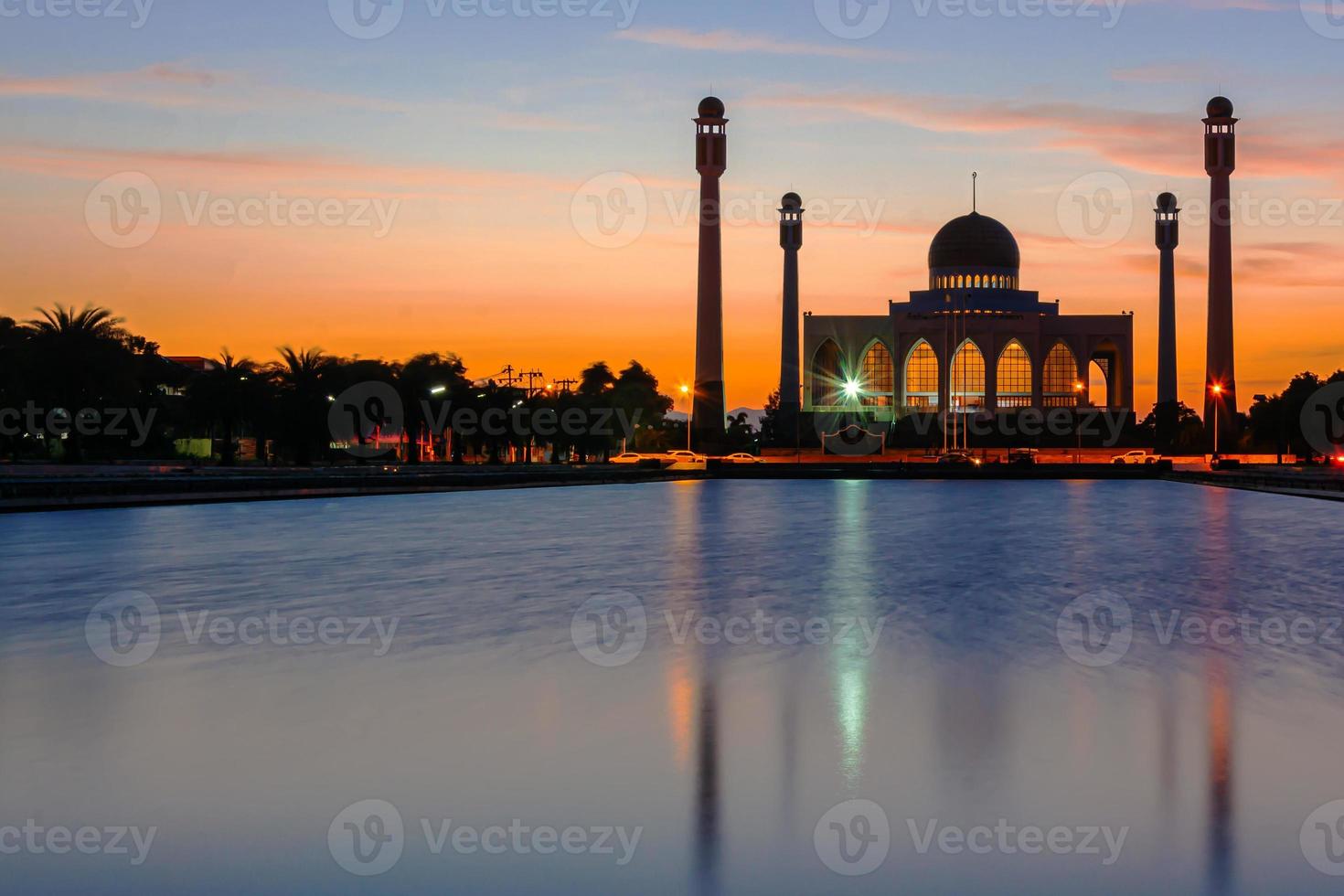 mosquée centrale de songkhla de jour comme de nuit avec un ciel coloré au coucher du soleil et les lumières de la mosquée et des reflets dans l'eau dans un concept de paysage emblématique photo