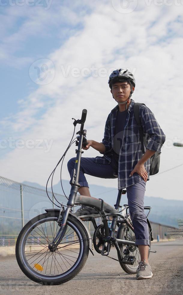 jeune homme asiatique avec sac à dos se reposer après avoir fait du vélo photo