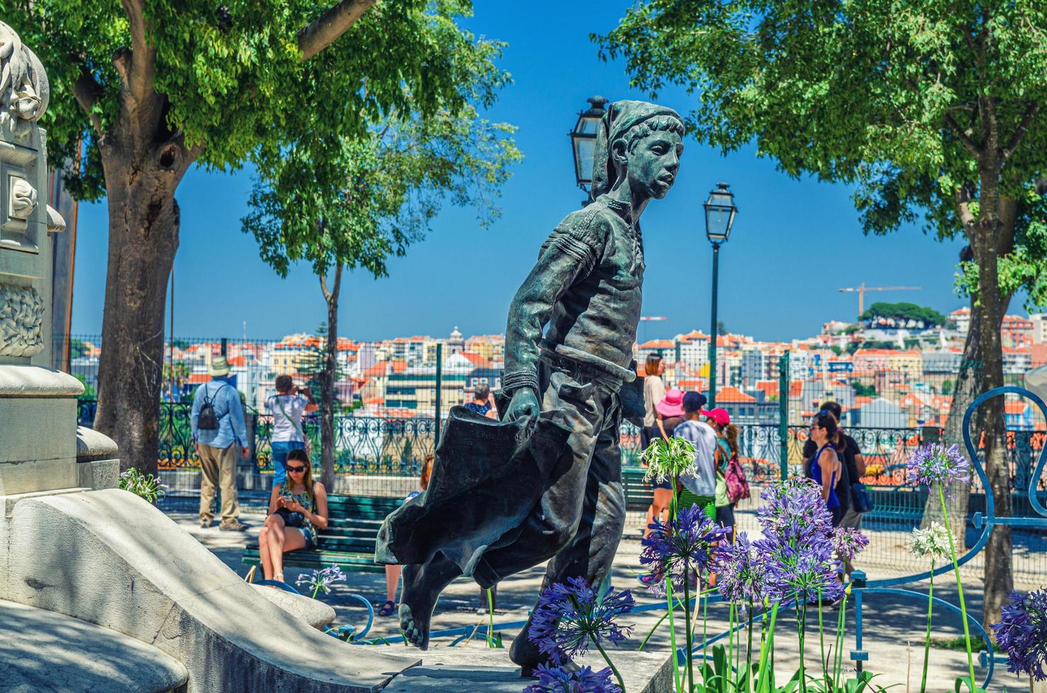 Lisbonne, portugal - 14 juin 2017 statue de garçon, arbres verts et touristes dans le parc-jardin miradouro de sao pedro de alcantara photo