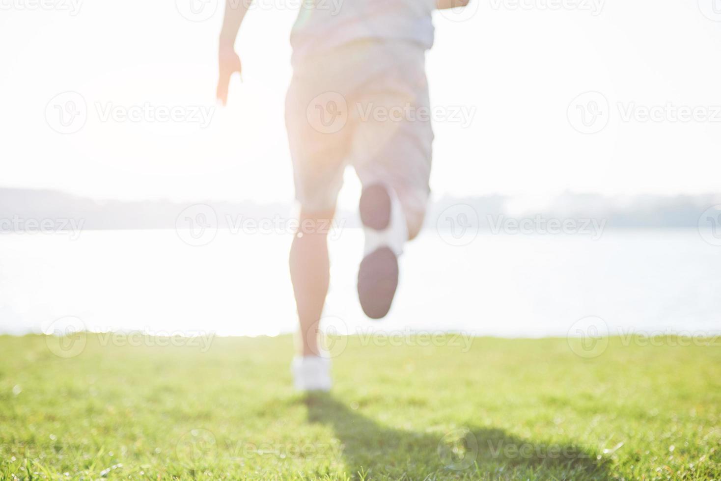 course de fond en plein air sous le soleil d'été concept pour l'exercice, la forme physique et un mode de vie sain. gros plan des pieds d'un homme qui court dans l'herbe photo