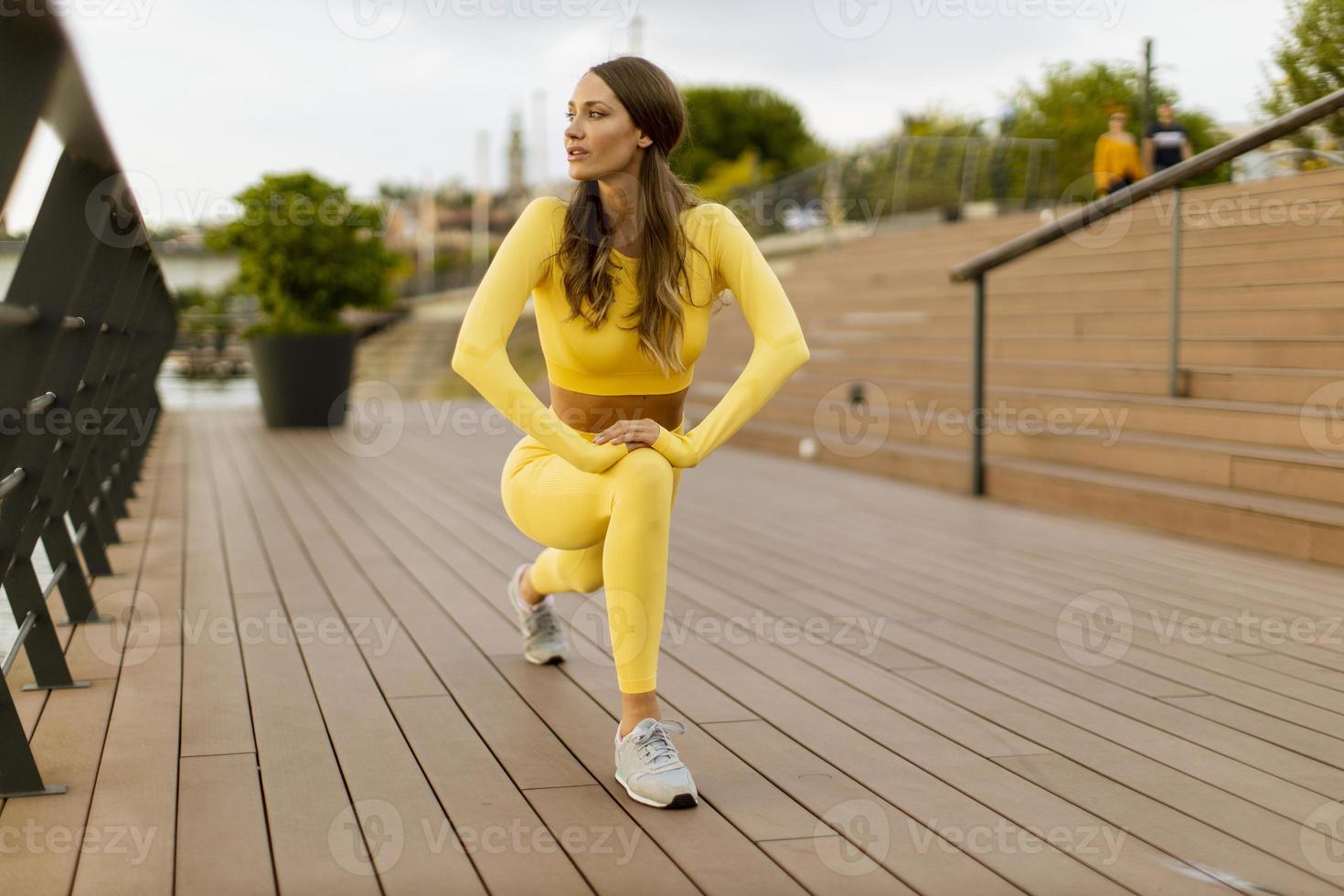 jeune femme ayant des exercices d'étirement sur la jetée au bord de la rivière photo