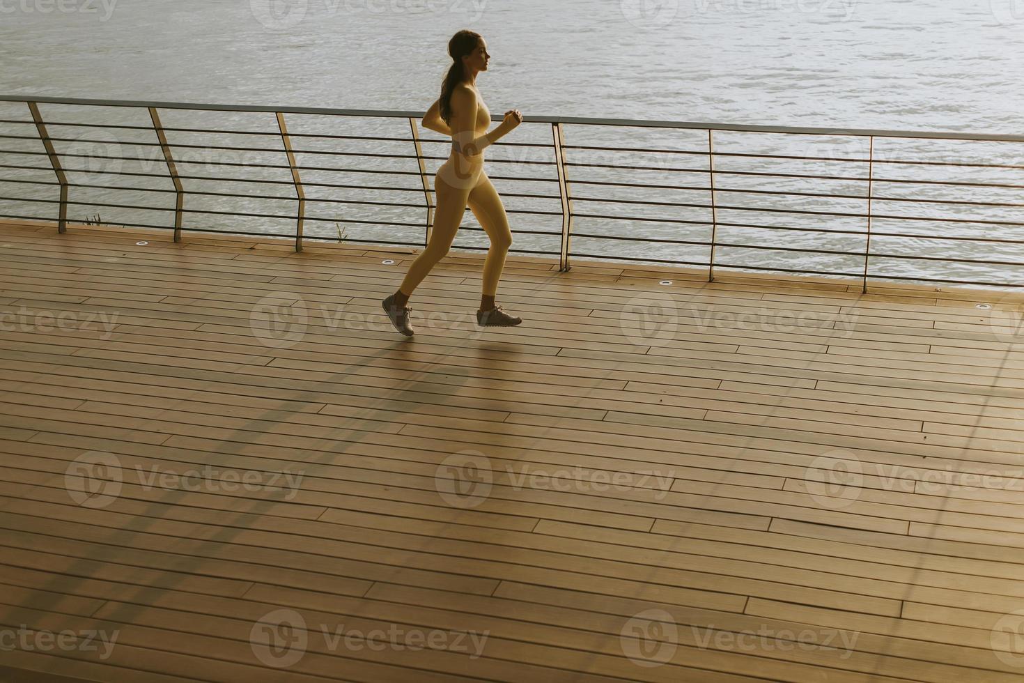 jeune femme courant sur la jetée au bord de la rivière photo