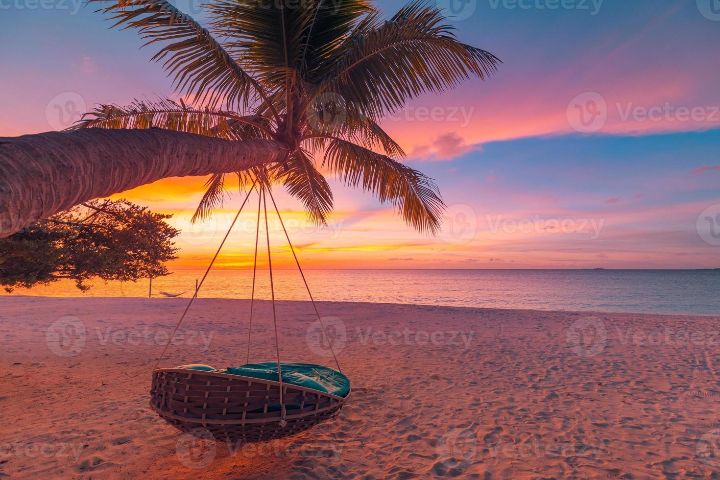 plage tropicale au coucher du soleil comme panorama de paysage d'été avec balançoire de plage ou hamac. ciel coloré, feuilles de palmier de sable et bannière de plage de mer calme. scène de plage romantique couple photo