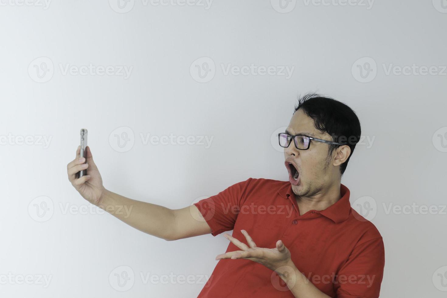 wow le visage d'un jeune homme asiatique a choqué ce qu'il voit dans le smartphone sur fond gris isolé. photo