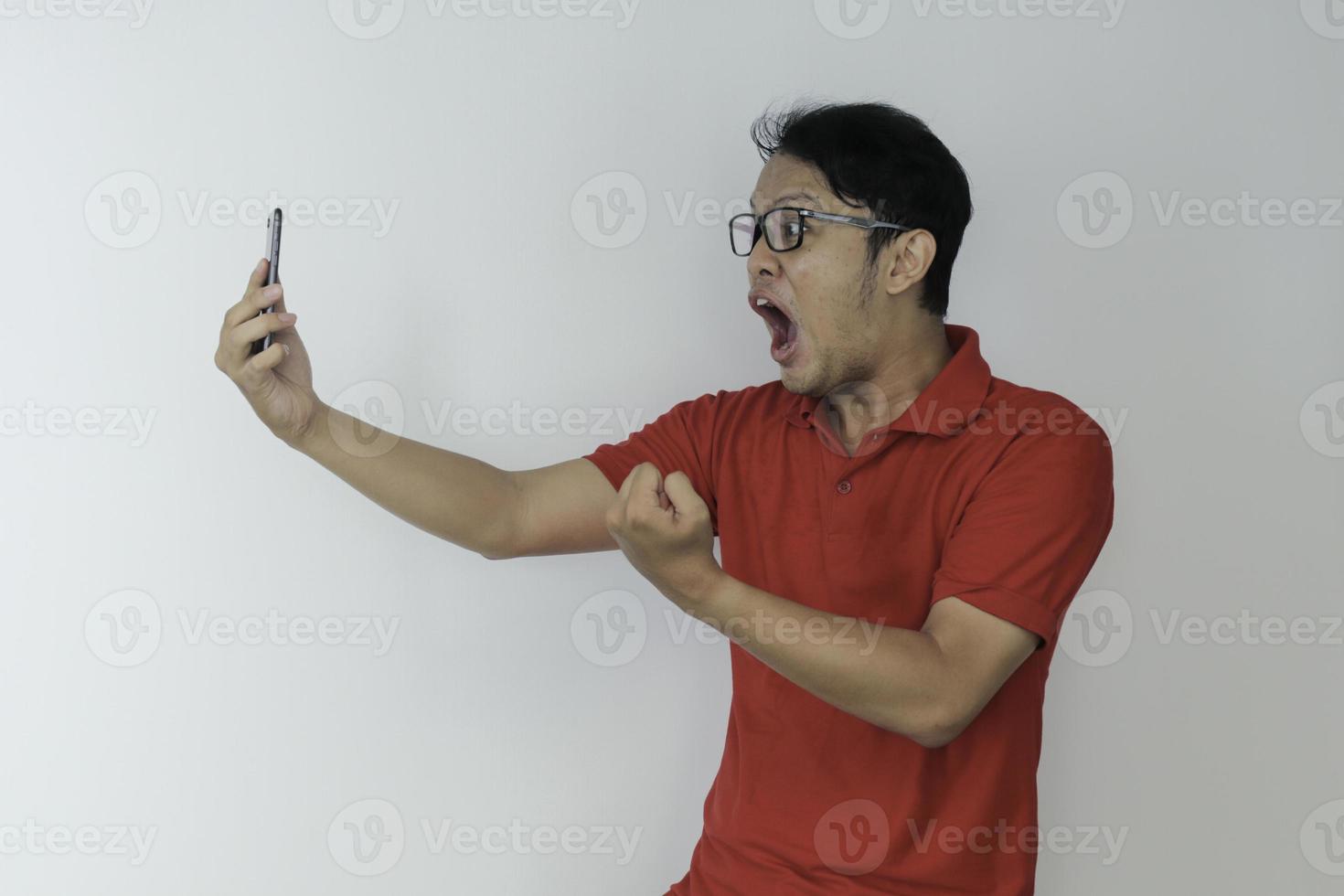 wow le visage d'un jeune homme asiatique a choqué ce qu'il voit dans le smartphone sur fond gris isolé. photo