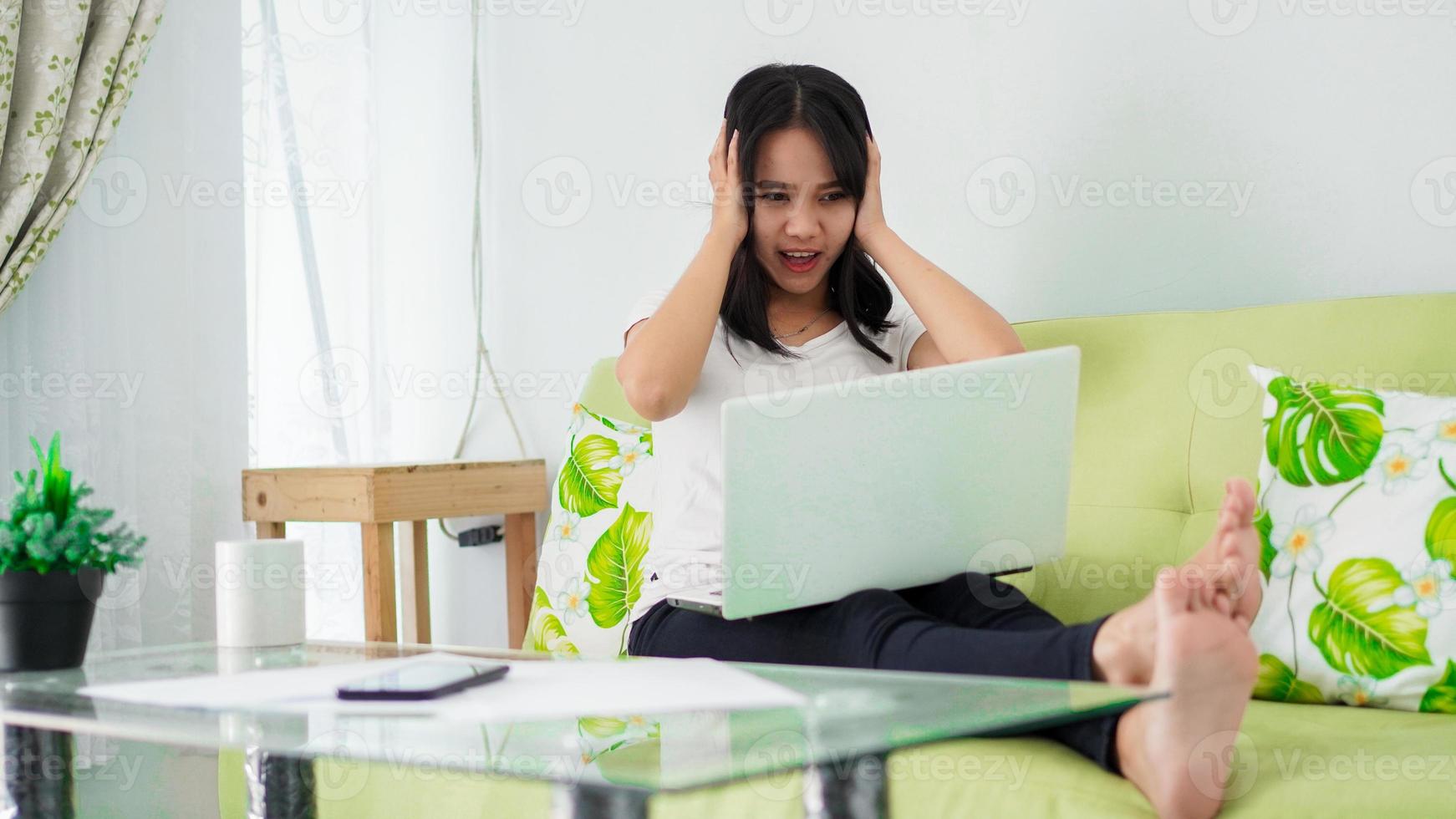 une femme asiatique stressée travaille à domicile avec un ordinateur à la maison photo