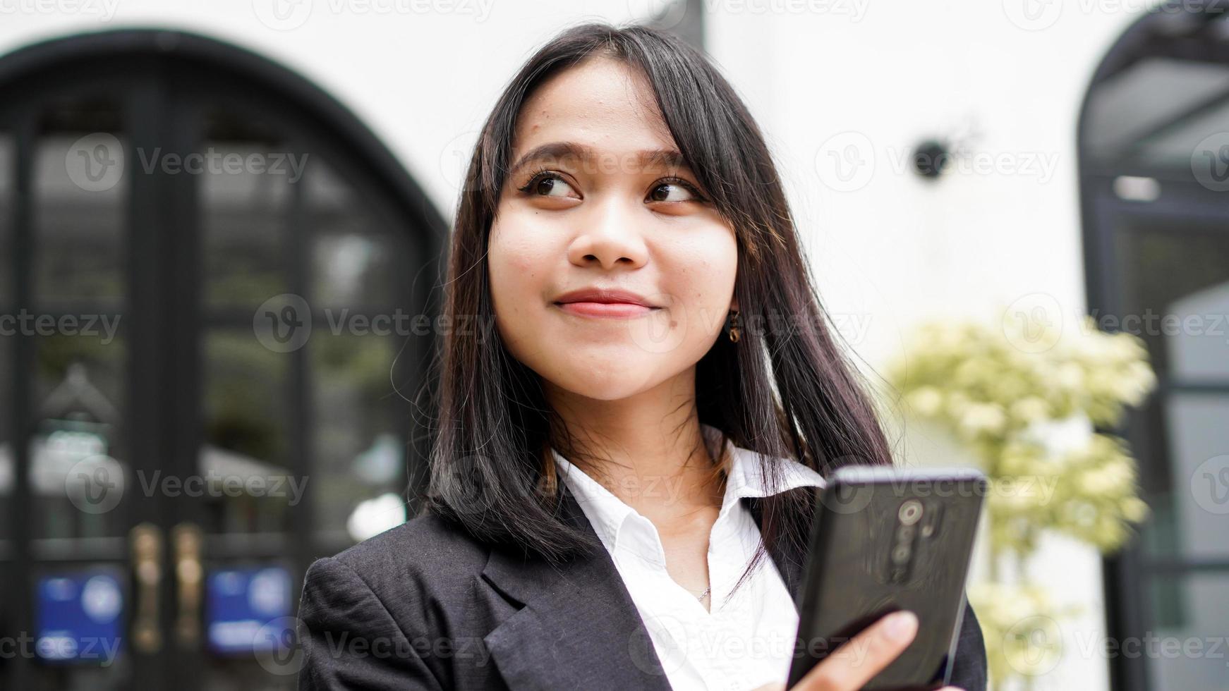 belle jeune femme d'affaires asiatique en costume debout au café avec téléphone et enveloppe brune photo