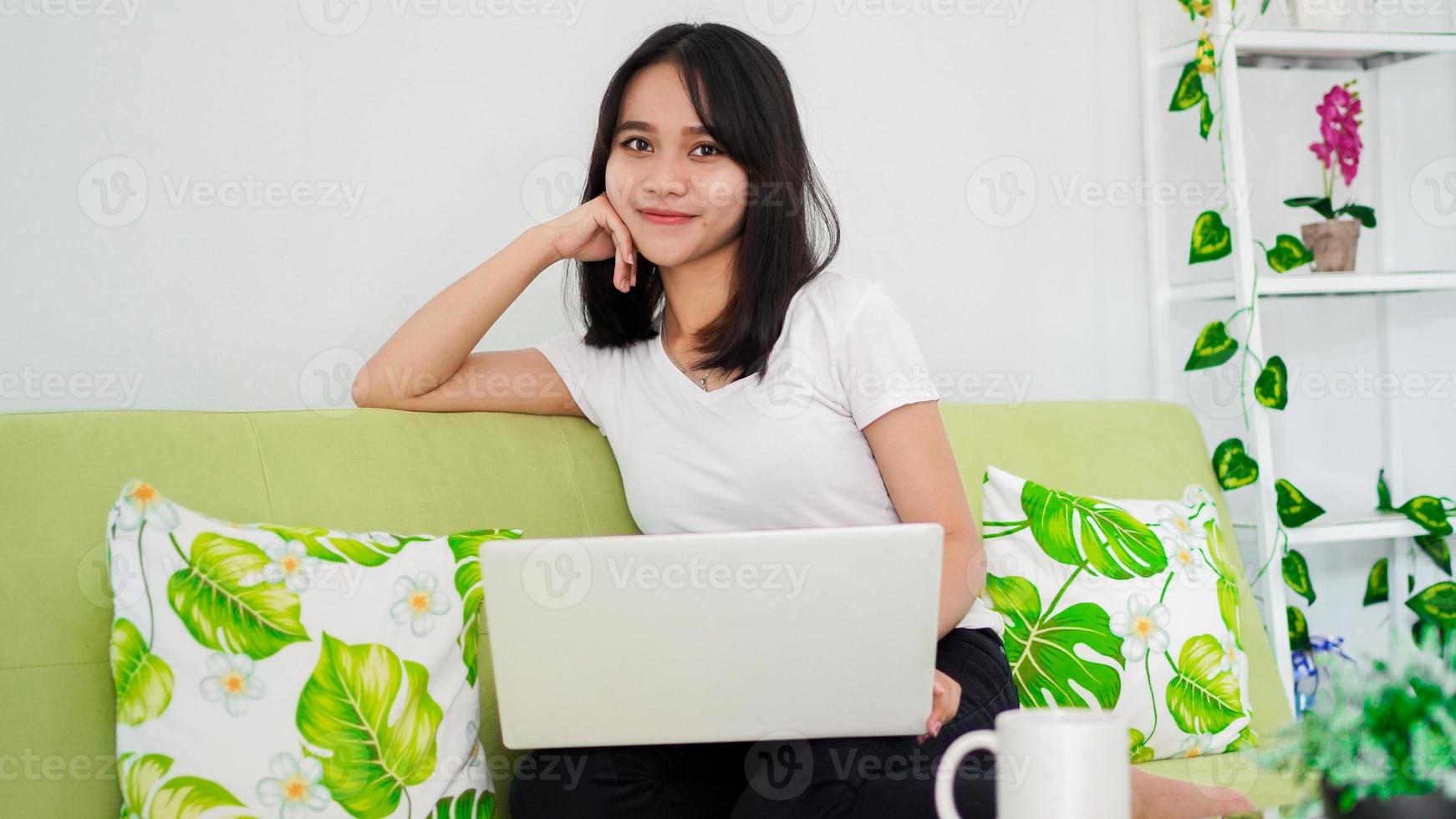 les femmes asiatiques assises sur une chaise travaillent à domicile sur un ordinateur portable et pensent à la solution du problème photo