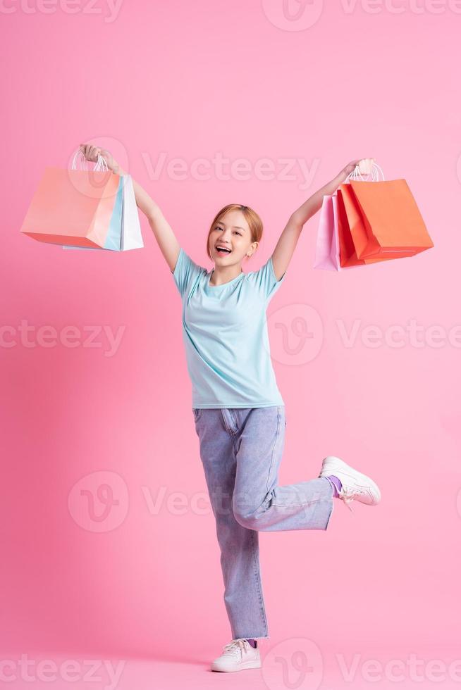 jeune femme asiatique tenant un sac à provisions sur fond rose photo