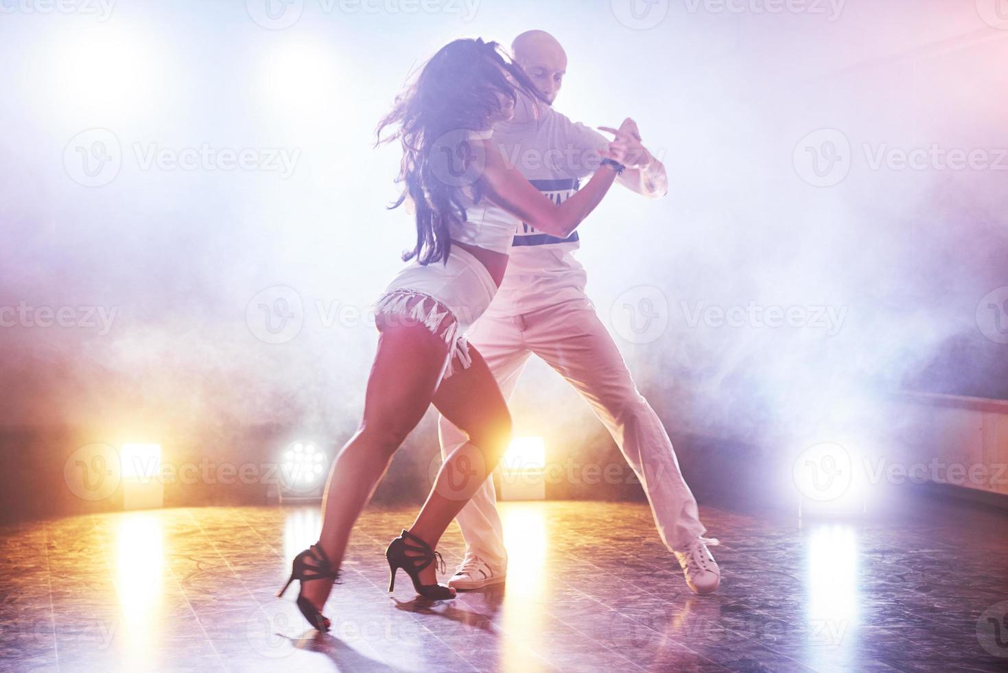 danseurs habiles se produisant dans la pièce sombre sous la lumière et la fumée du concert. couple sensuel exécutant une danse contemporaine artistique et émotionnelle photo