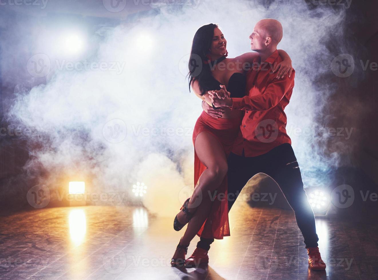 danseurs habiles se produisant dans la pièce sombre sous la lumière et la fumée du concert. couple sensuel exécutant une danse contemporaine artistique et émotionnelle photo