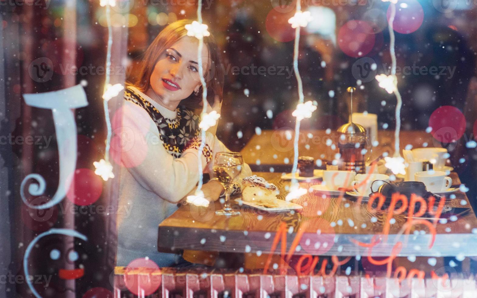 belle jeune femme assise dans un café, buvant du café. noël, bonne année, saint valentin, concept de vacances d'hiver photo