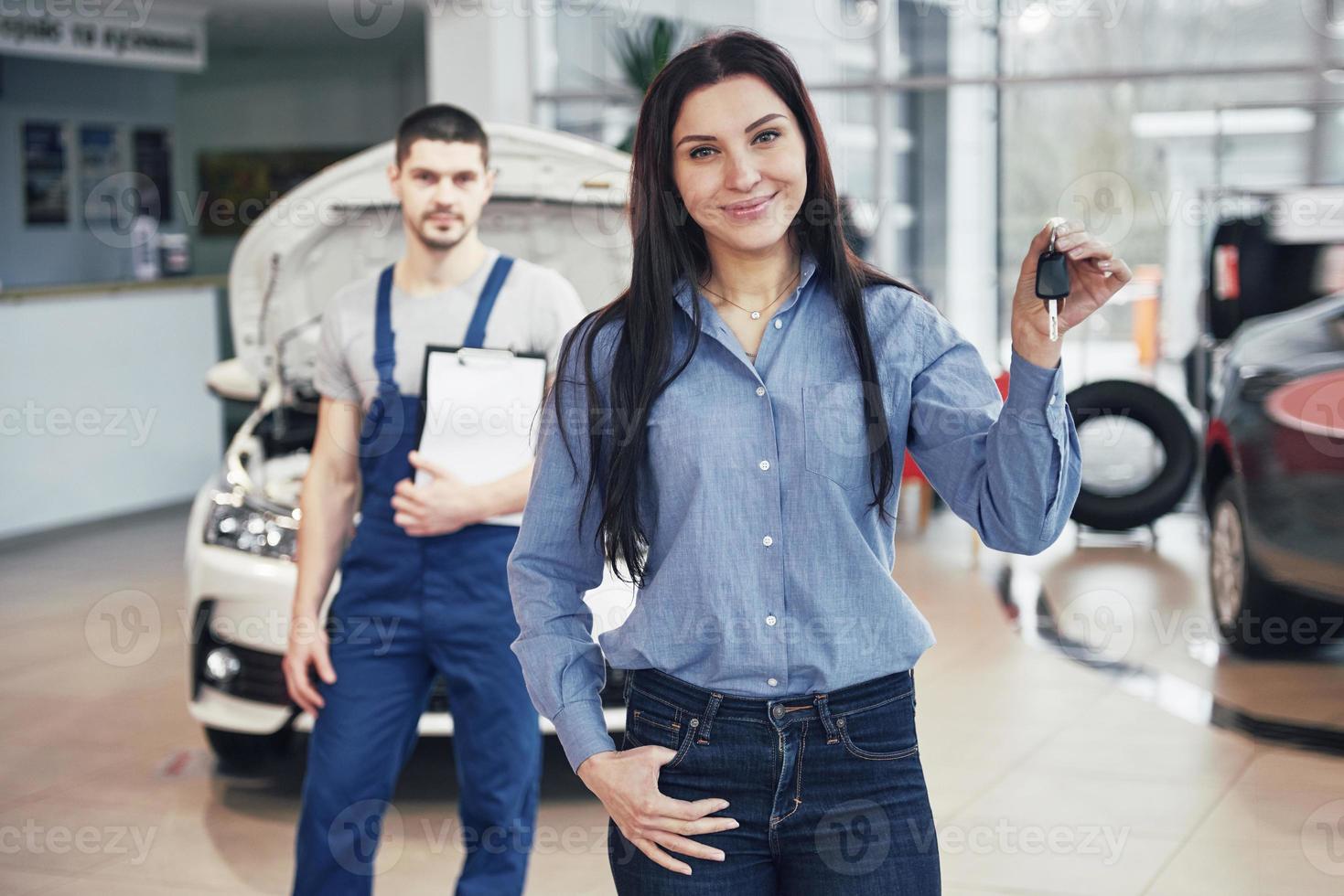 une jeune femme prend une voiture du centre de service automobile. elle est contente car le travail est parfaitement fait photo