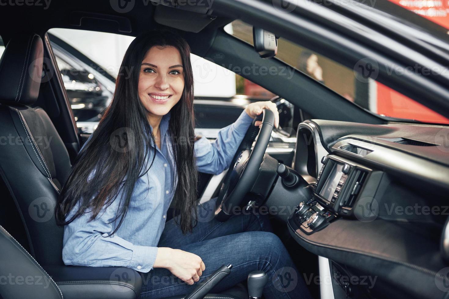 concept d'entreprise automobile, de vente de voitures, de consommation et de personnes - femme heureuse prenant la clé de voiture du concessionnaire dans le salon de l'auto ou le salon photo