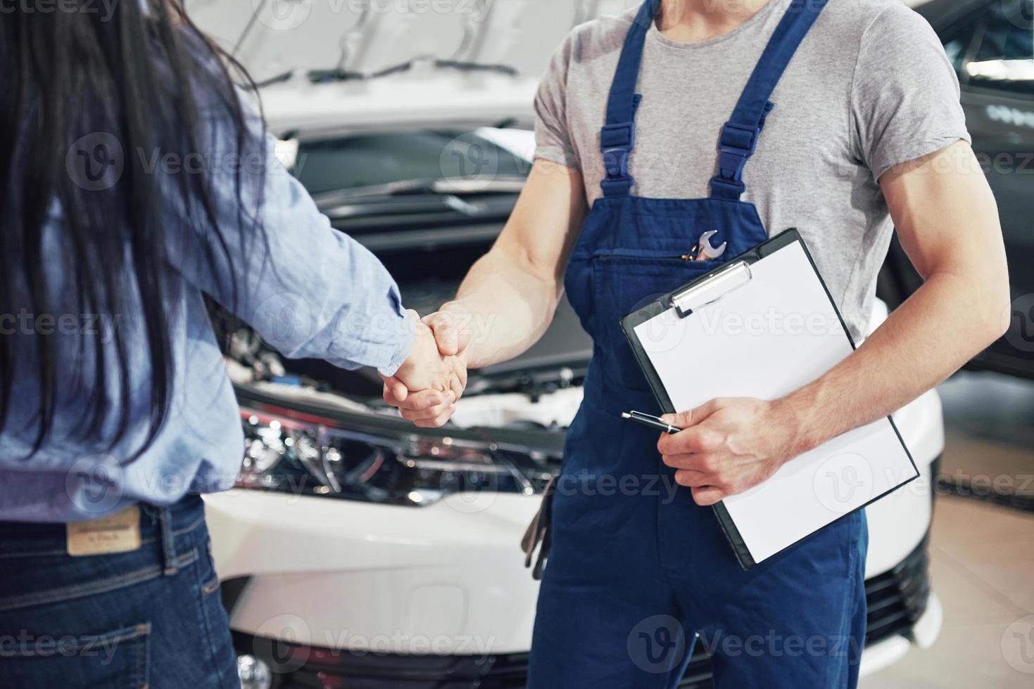 mari mécanicien automobile et cliente concluent un accord sur la réparation de la voiture photo