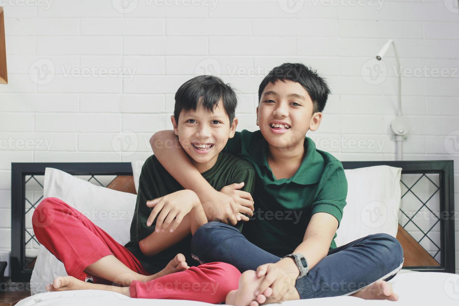 deux heureux frère asiatique assis et souriant ensemble sur le lit photo