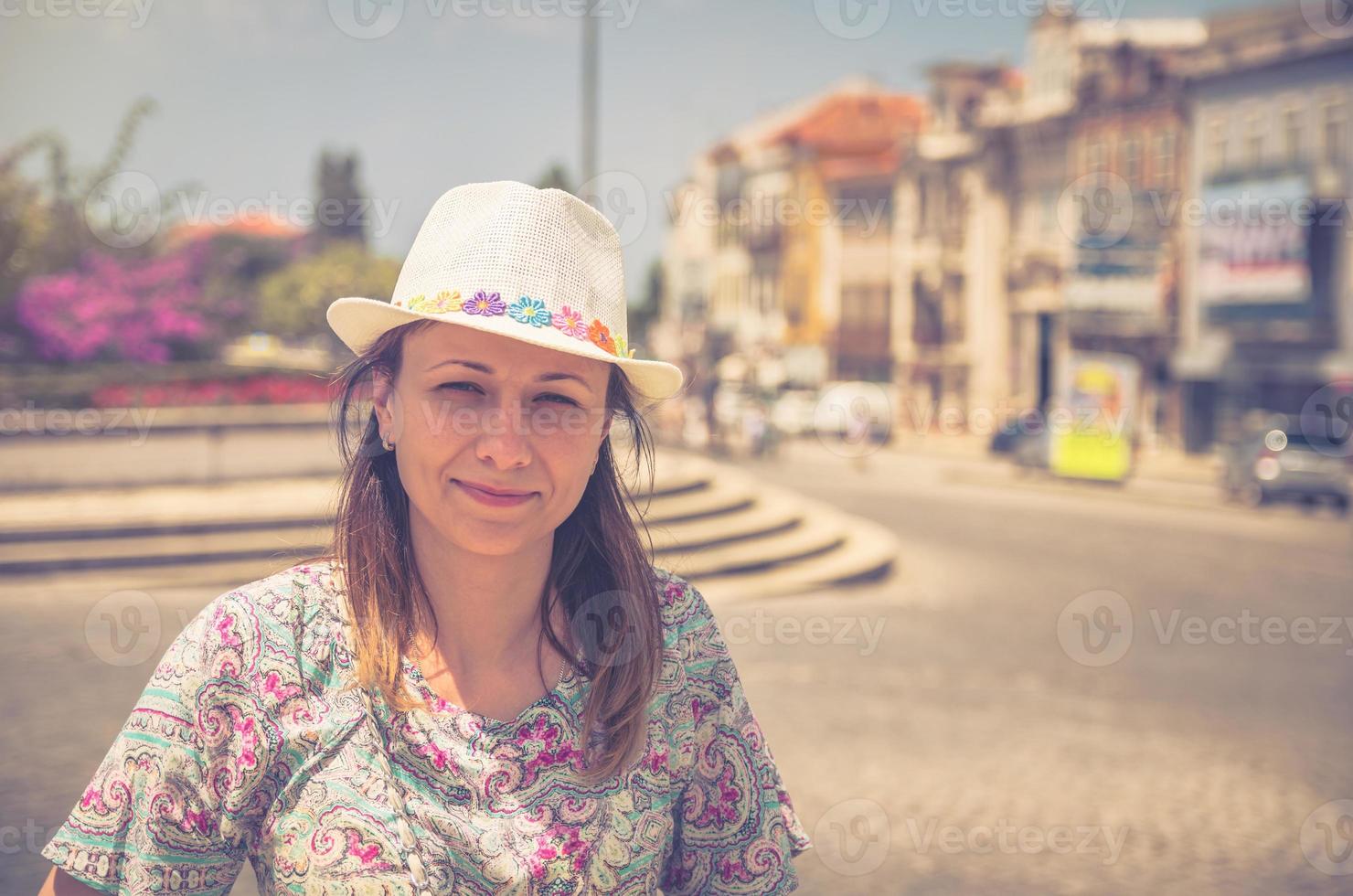 jeune femme voyageur avec chapeau regardant la caméra posant et souriant dans les rues de la ville d'aveiro au portugal photo