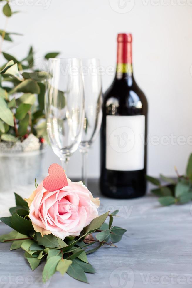 composition avec verre, fleurs et bouteille de vigne sur fond de béton gris. photo