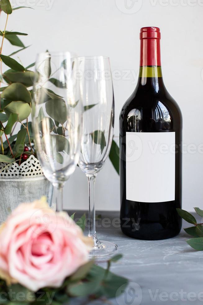 composition avec verre, fleurs et bouteille de vigne sur fond de béton gris. photo