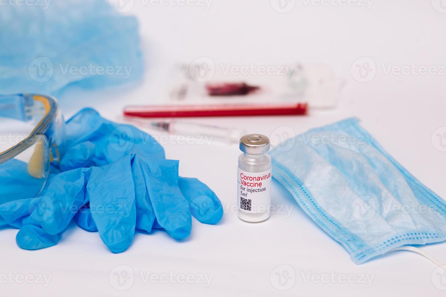 vaccin contre le coronavirus. préparation médicale en ampoule. traitement de la maladie, covid-19. le vaccin sur un fond blanc et sur le fond d'une seringue, des gants en caoutchouc et des lunettes photo