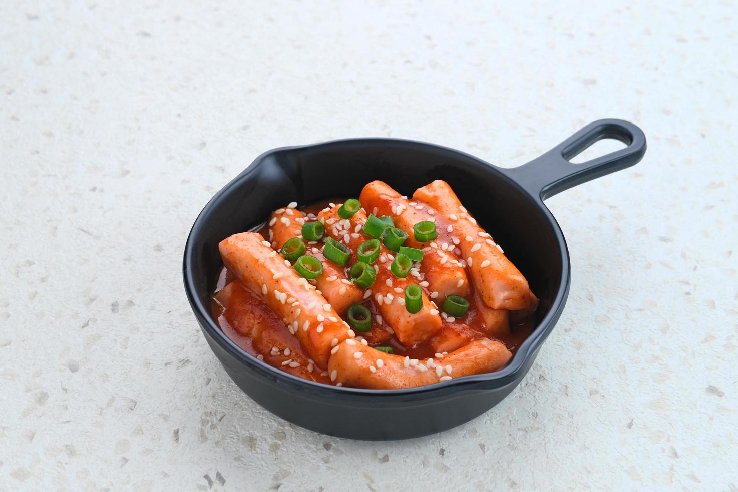 tteokbokki ou topokki, bâtonnet de gâteau de riz sauté, cuisine de rue coréenne populaire avec sauce gochujang épicée et graines de sésame. photo