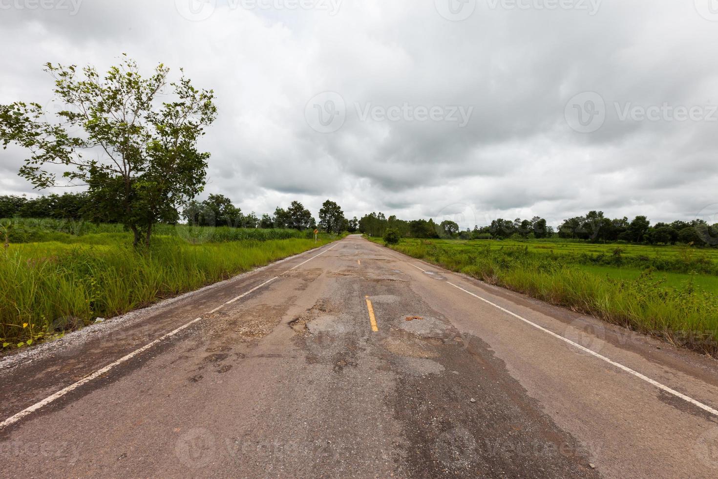 Route asphaltée endommagée avec des nids de poule photo