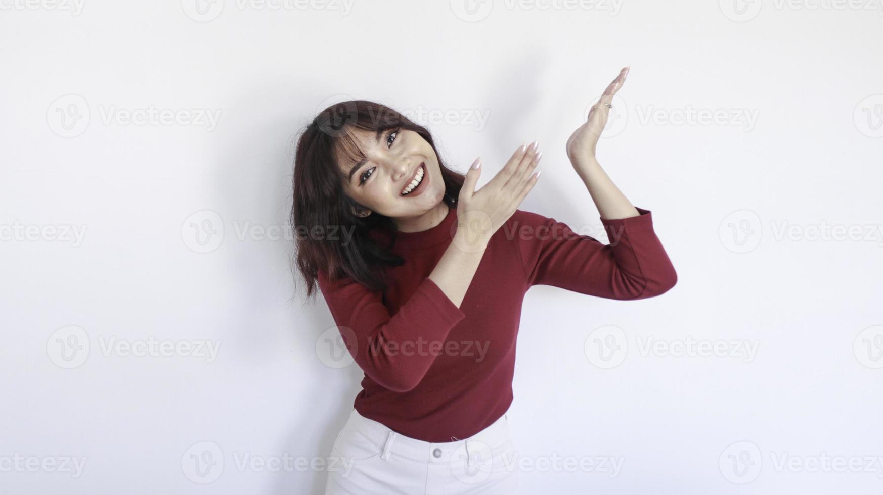 heureux pointant au-dessus d'une belle fille asiatique avec une chemise rouge sur fond blanc photo