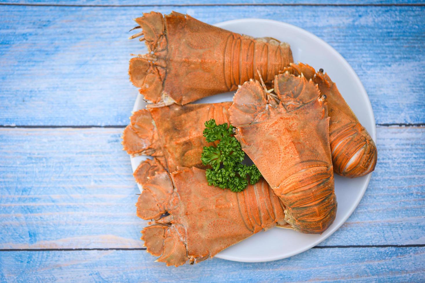 Crevettes de homard à tête plate servies sur une assiette blanche, langouste fraîche bouillie à tête plate avec persil - vue de dessus photo